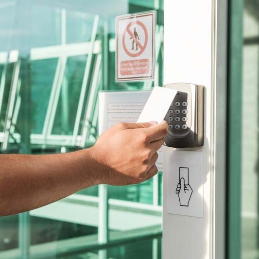 Hand using security key card scanning to open the door to entering private building . Home and building security system