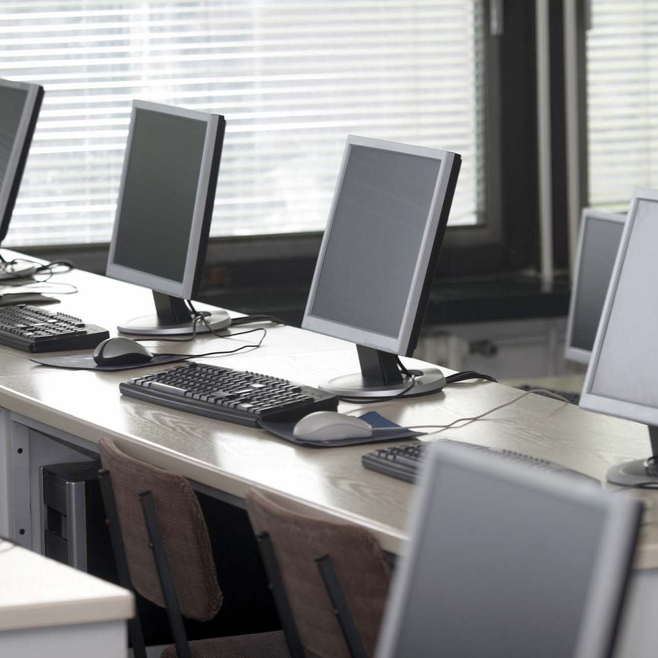 Row of computers on desk in a school class room